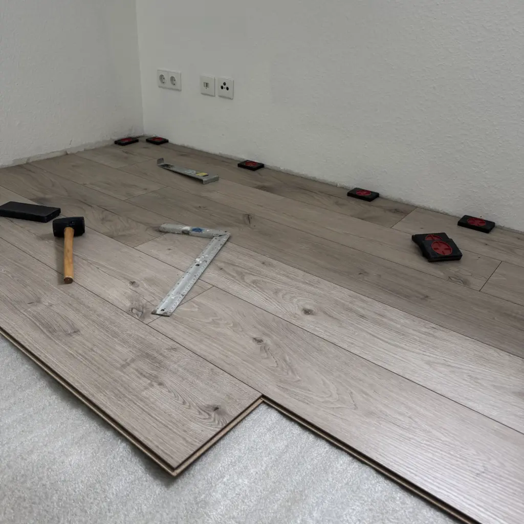 Laminatverlegung in Arbeit im Schlafzimmer in Neumünster mit Werkzeug und Abstandskeilen