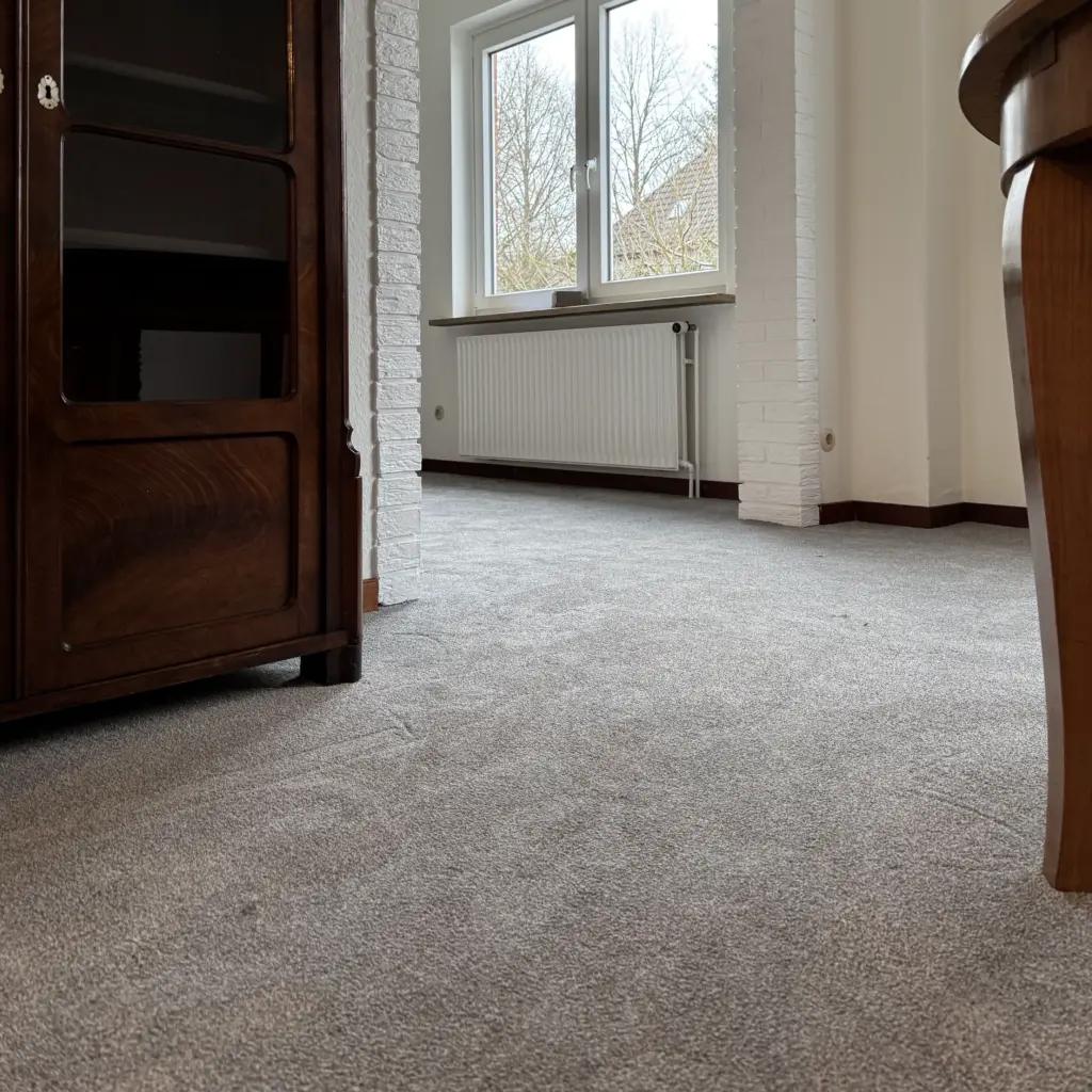 Passgenau verlegter Teppichboden in Neumünster mit sauberem Abschluss an Wand und Möbeln