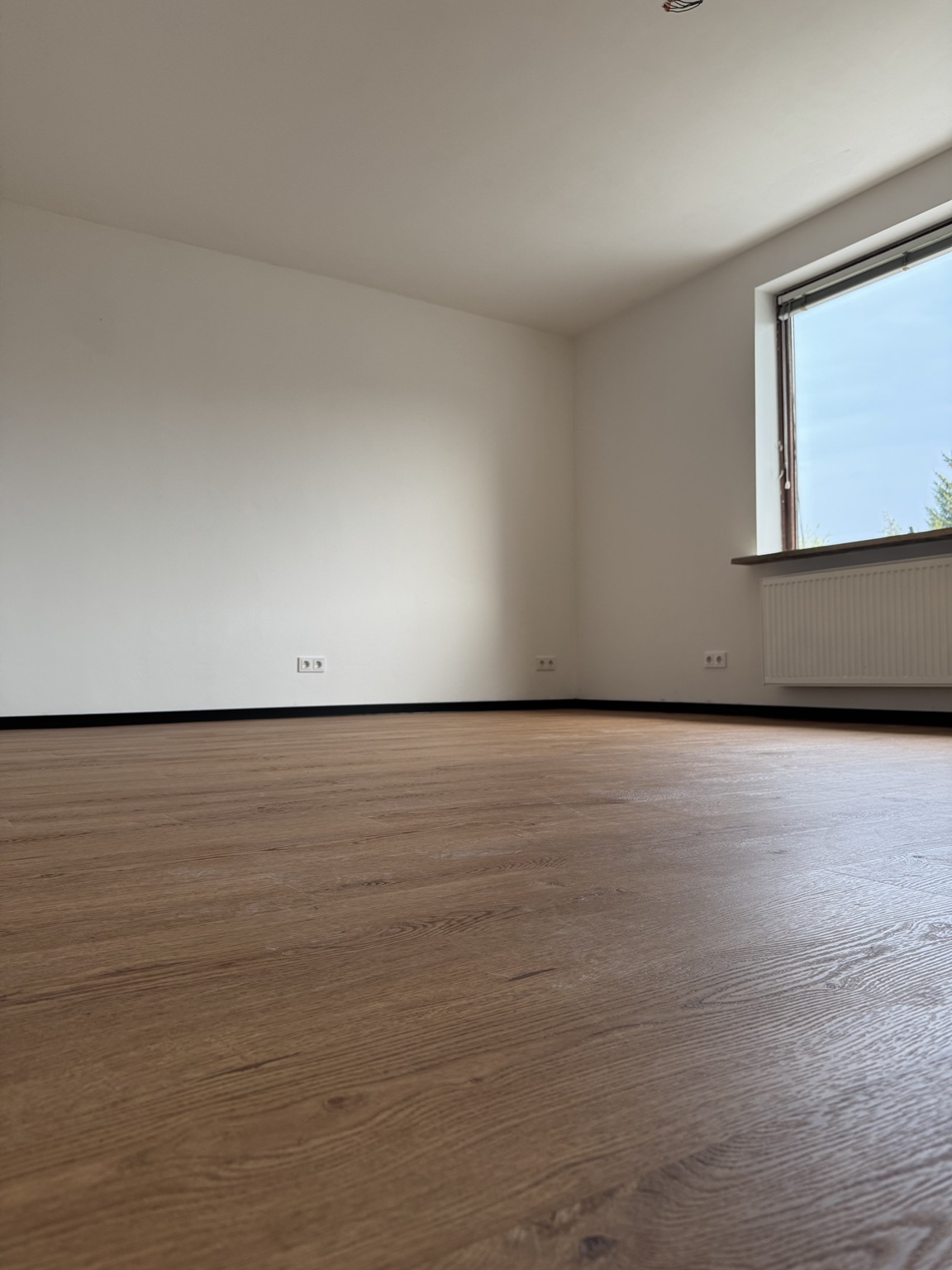 Schwarze Sockelleisten als bewusster Kontrast zu einem Vinylboden in Holzoptik